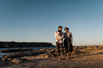 Parents walking with newborn baby during sunset at Little Bay, Sydney