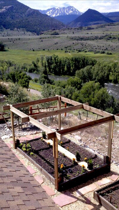 A garden bed  full of soil with vertical wooden beams. 