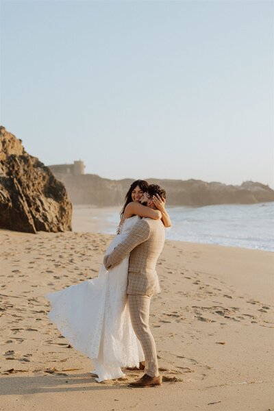 groom lifting bride and spinning her on a beach