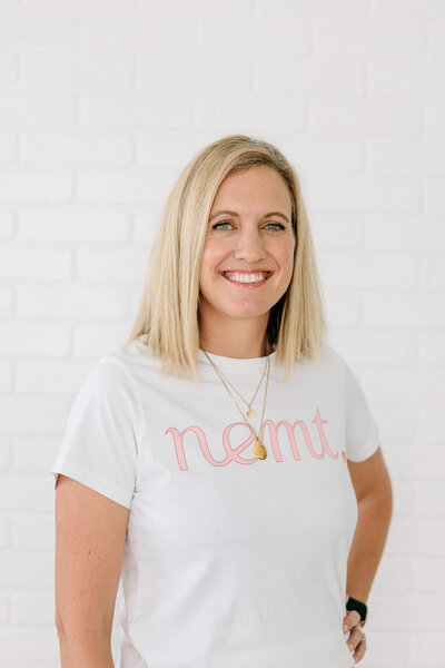 Blonde lady smiling during her headshot against a white brick wall in a studio in Houston Texas