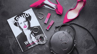 flat lay shot of fashion items such as magazine, pink shoes and lipstick, silver jewelries