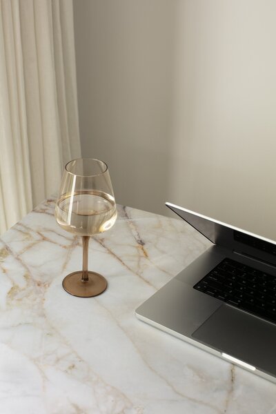 Glass of wine next to a laptop 