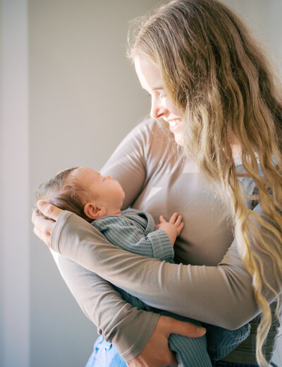 Mother holding in her arms her newborn daughter while looking at her smiling
