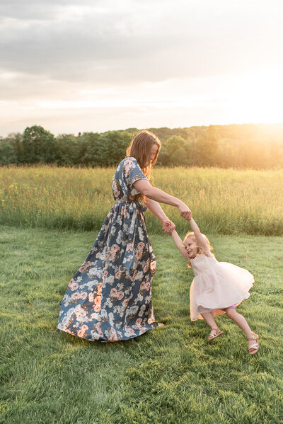 Mother spinning daughter in open field