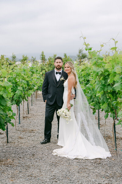 bride and groom in  traditional black and white standing in an editorial pose in a vineyard