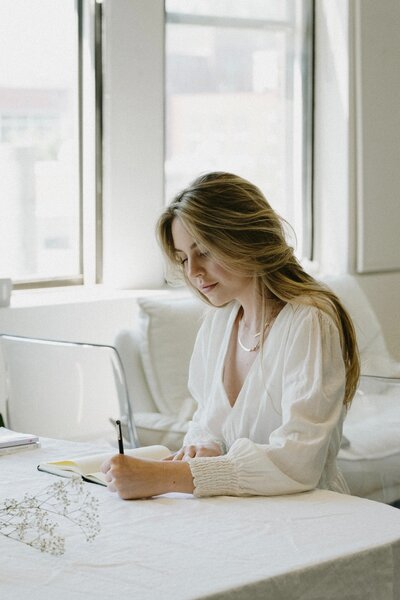 A woman sitting at a desk writing.