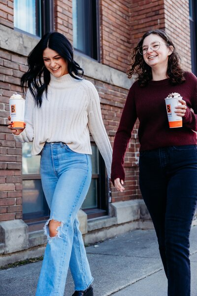Two friends walking down the street with their Biggby Coffee.