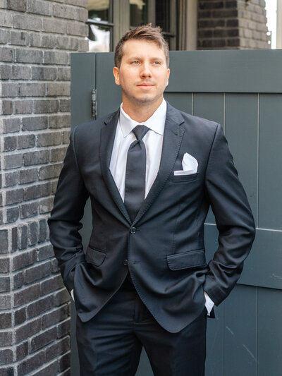room in black suit posing outside Lido House in Newport Beach, hands in pockets, looking confident before the ceremony