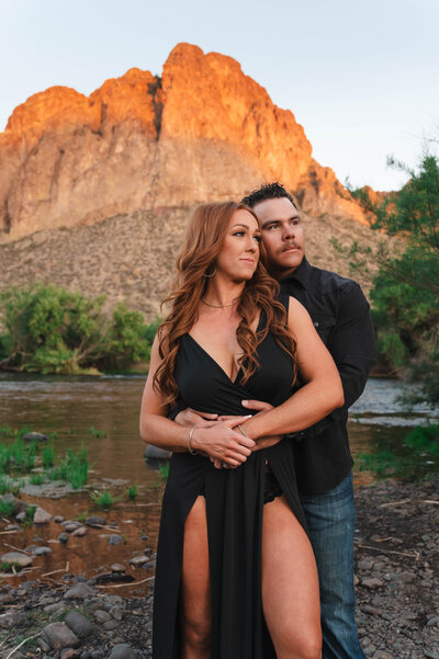 Engaged couple holding hands and smiling during golden hour photo session.