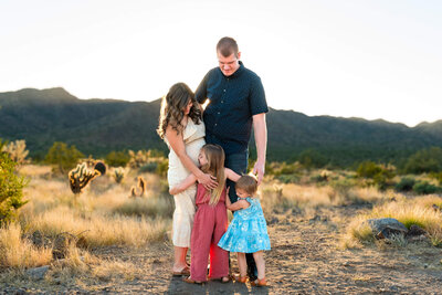 Young family hugging each other in the Phoenix desert at sunset