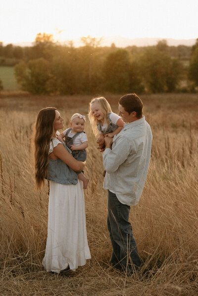 Family of four enjoying a candid moment during sunset in Jefferson, Oregon, with warm golden light illuminating the scenic backdrop.