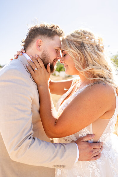 A bride and groom share a quiet moment together while holding each other close. They are outside in a field of tall yellow grass.