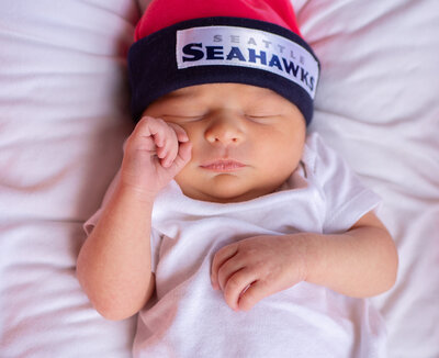 Sleeping baby wearing a Seattle Seahawks beanie. Seattle Newborn Photography