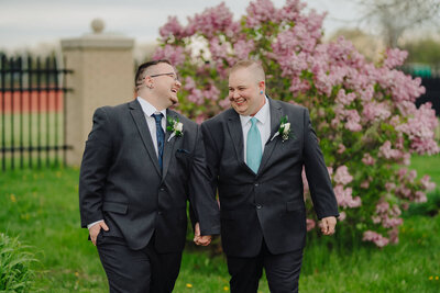Grooms holding hands walking along