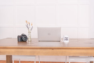 Personal Brand Worksheet - a laptop, mug, DSLR, and a small vase are on a desk.