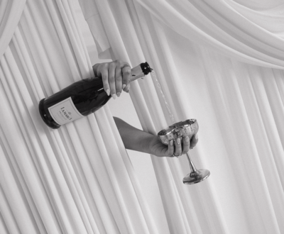 Champagne pouring into coupe glass in front of draping