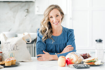 Blonde haired woman leaning on counter with blue shirt