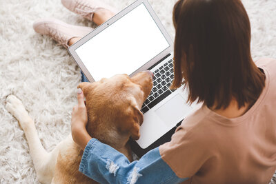 Woman with an open lap top sitting next to her dog