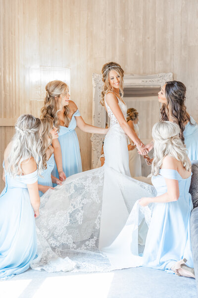 bright light and airy wedding photo of bride with bridesmaids getting ready in bridal suite