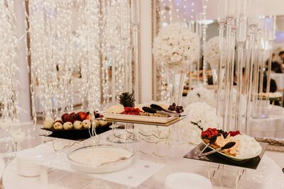 Dessert table with fruits, dip, and white floral decor at a wedding reception