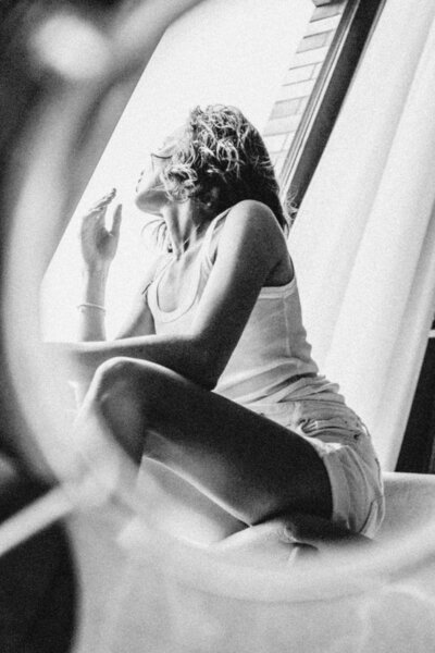 Authentischer Moment, der eine selbstbewusste Frau durch einen Spiegel zeigt, wie sie sich aus dem Fenster lehnt