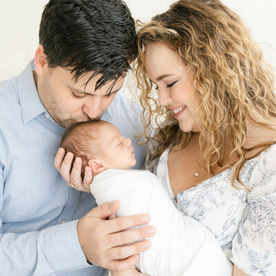 Dad kisses newborn baby during photo shoot with Louisville KY newborn and family photographer Julie Brock