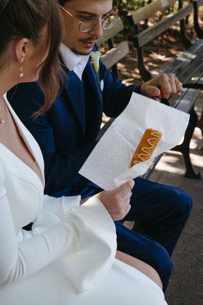Bride and groom eating corn dog in Central Park NYC