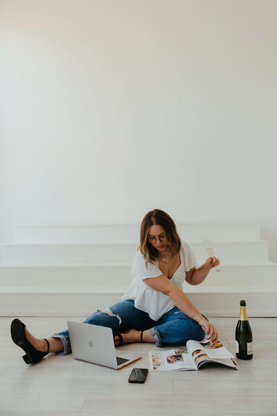 Wedding planner Rachel looks at a magazine with a glass of champagne, representing her full service wedding planning and wedding coordinator services. 