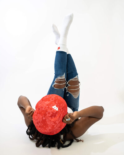Model laying down with feet up wearing red patterned bucket hat