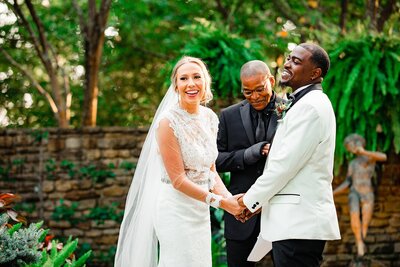 Joyful moment of bride and groom holding hands and laughing together during their vows
