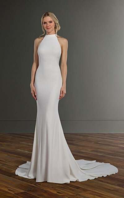 CHIC WEDDING DRESS WITH DRAPED COWL BACK Giving us all of the modern royal vibes is this chic wedding dress from Martina Liana. The clean silhouette of stretch crepe with comfort fit lining offers maximum comfort for an effortless feel, while curved linear seaming throughout the front and back provide structure and shape to enhance your figure. The high-halter neckline is high-fashion and all-regal, following into a stunning cowl detail in back with a slight peek-a-boo element. Fabric-covered buttons run the length of the back and through the short, supple train for an elevated and utterly refined bridal finish.