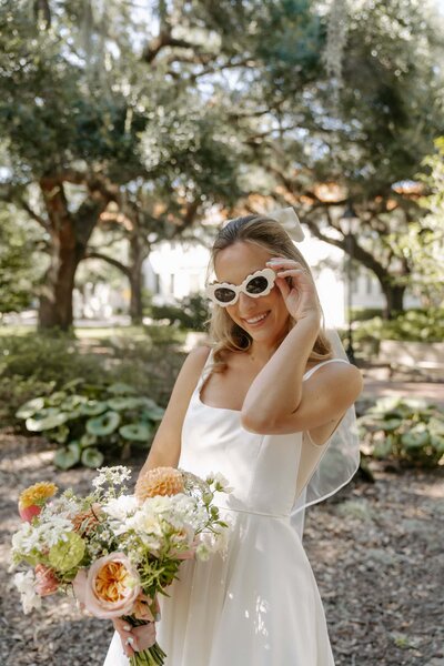 Bride holding sunglasses and bouquet