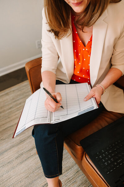Lindsay sitting on a touch writing in a planner