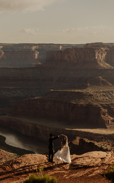 Dead Horse Point, Moab, Utah Elopement photos of couple spinning on a cliffside view