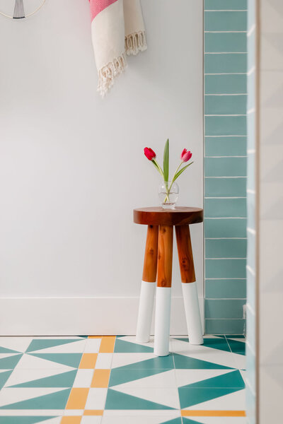 Small wooden stool on blue, white and yellow tile
