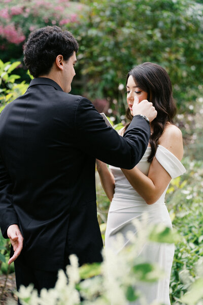 Groom wipes bride’s tear during intimate first look at Sapphire Creek Winery wedding.

