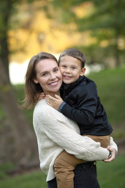Mother holding son and smiling cheek to cheek.