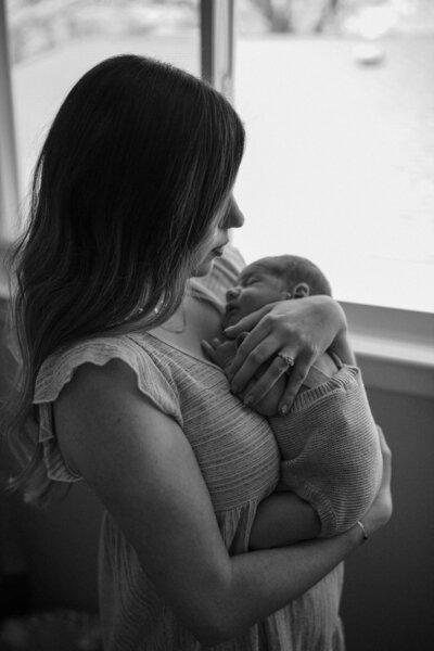 Mom holding newborn baby in nursery by Taylor lynn Studios