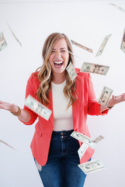woman laughing hysterically as dollar bills fly around