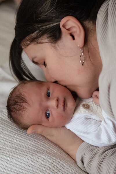 Een vrouw kust liefdevol een baby, wat een moment van genegenheid en tederheid vastlegt.