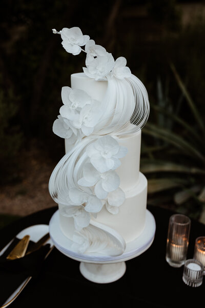 3 tier all white wedding cake with cascading wafer paper waves and handcrafted white wafer paper orchids