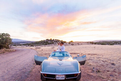 Bride and groom sit in a convertible car with the sunsetting behind them. beautiful sunset skies. taken by kate legters photography