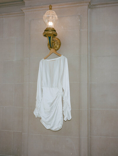A short silky wedding dress hung up at a city hall elopement