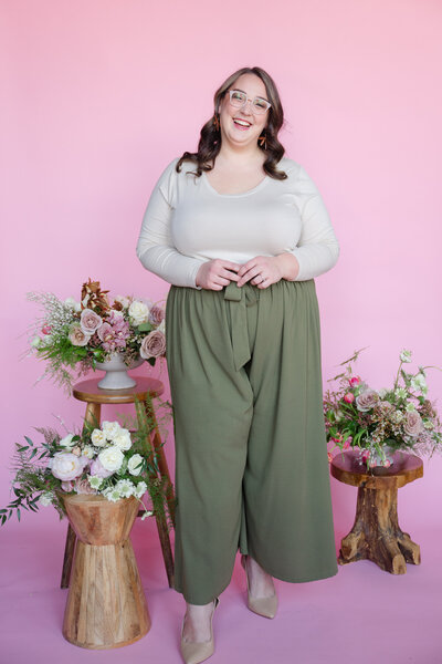 A person smiling and standing next to small stools with flowers on them.