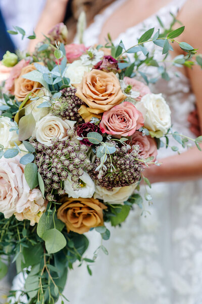 Close-up of a bouquet with roses and greenery in warm tones.