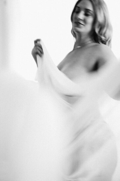 maternity session with woman dancing with sheer sheet in black in white