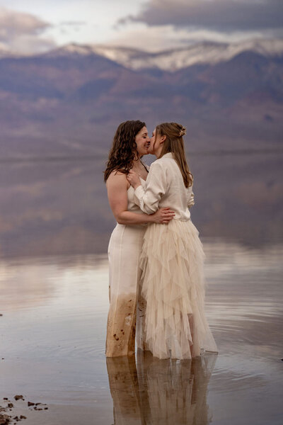 wo brides walking hand-in-hand through the otherworldly Badwater Basin in Death Valley, the lowest point in North America