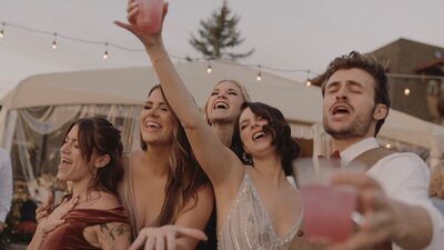Wedding party singing while holding drinks