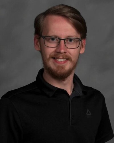 A headshot of a person with glasses smiling 