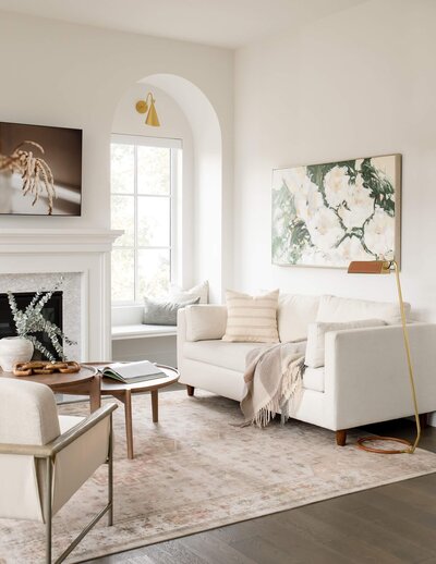 A light and airy living room with white custom upholstered pieces and floral artwork. 